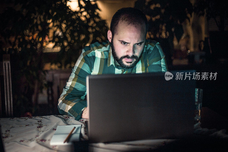 Man working and using laptop at home late at night